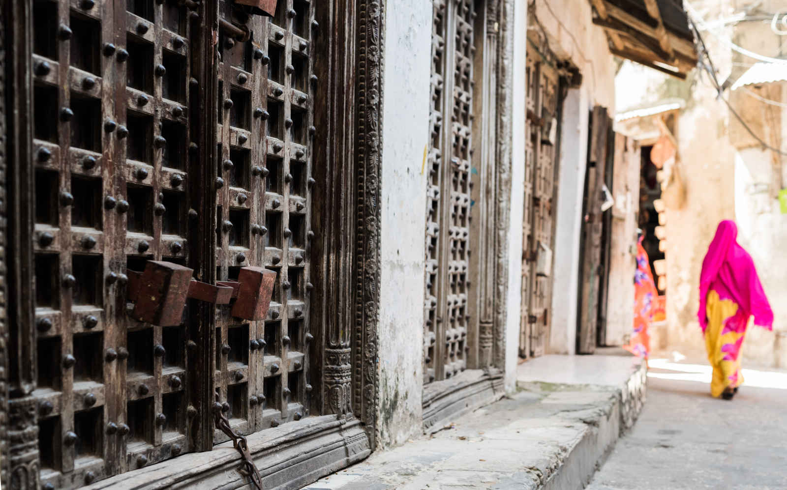 Portes anciennes et femme marchant dans la rue Stone Town Zanzibar